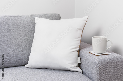 Blank white pillow on a couch with a tea cup. photo