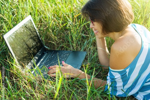 Adult beautiful woman using laptop in nature, outdoor portrait