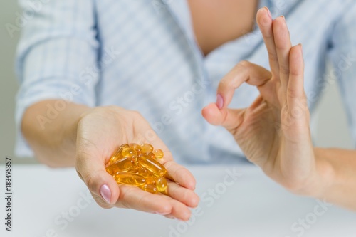 Woman's hand holding Omega 3 capsule and a sign ok