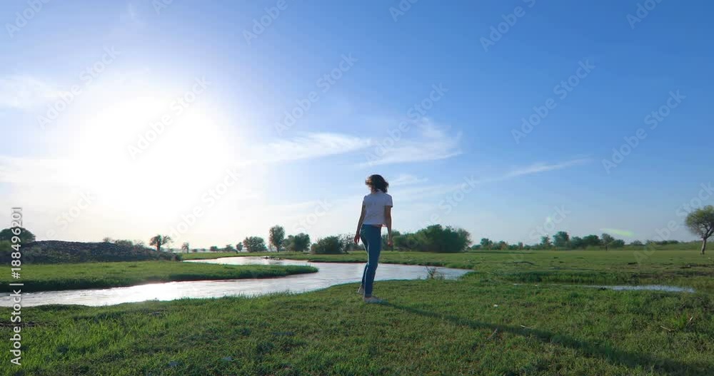 Young woman on green grass field with river Young woman on green grass field with river
