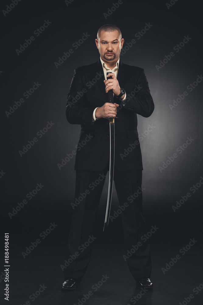serious yakuza member in suit holding katana sword on black serious yakuza member in suit holding katana sword on black