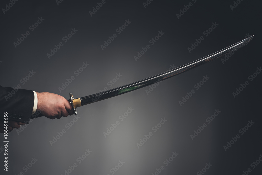 Fototapeta premium cropped shot of man holding katana sword on black