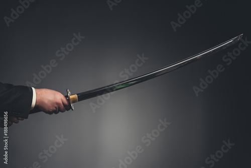 cropped shot of man holding katana sword on black photo