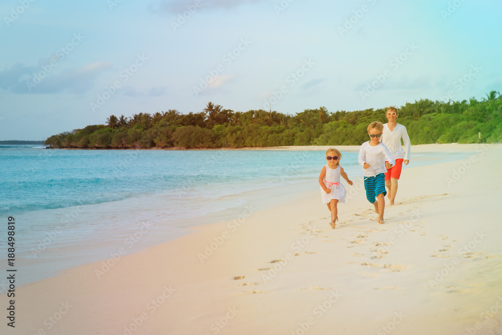 father with little son and daughter run at beach