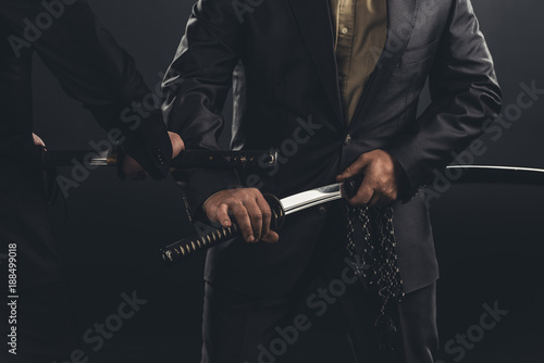 cropped shot of modern samurai taking out their swords isolated on black