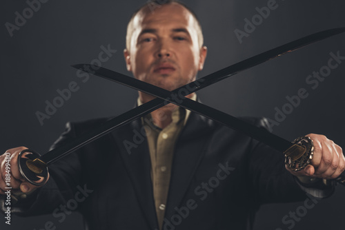 close-up shot of man in suit with katana sword on black