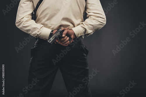 back view of man in shirt holding gun behind back