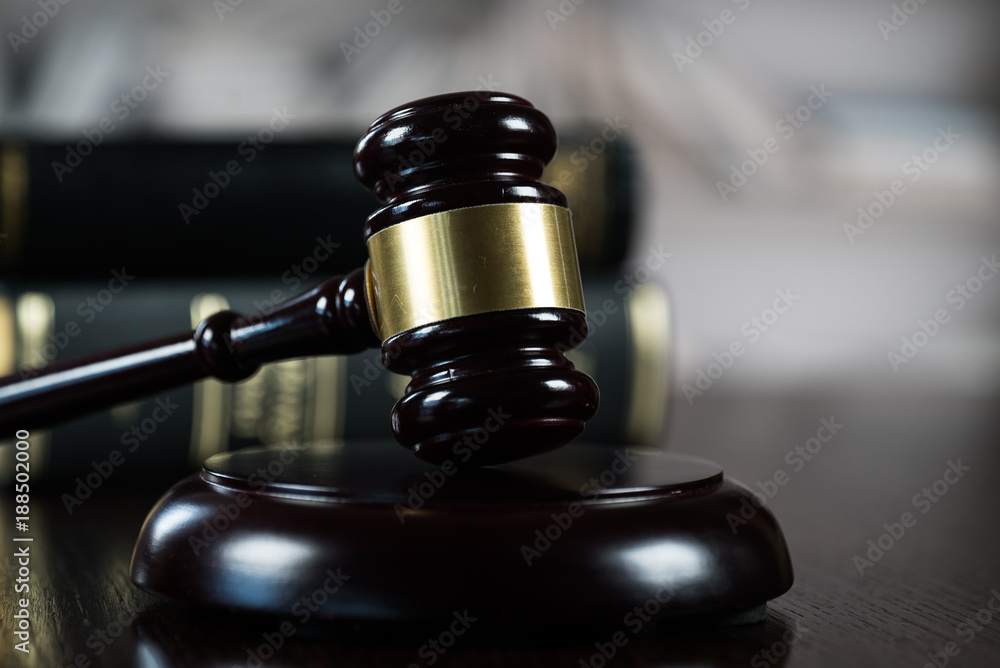 Law and Justice concept. Mallet of the judge, books, scales of justice. Gray stone background, reflections on the floor, place for typography. Courtroom theme.