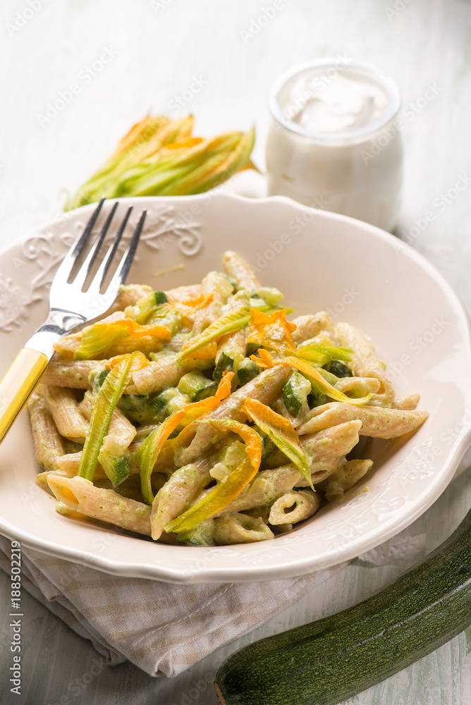 pasta with zucchinis flowers and cream sauce or yogurt, selective background