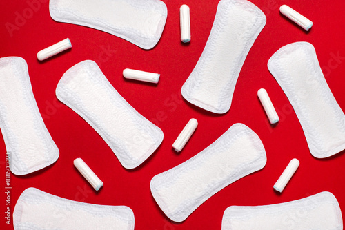 Menstruation, protection means. Pile of pads and tampons on red background
