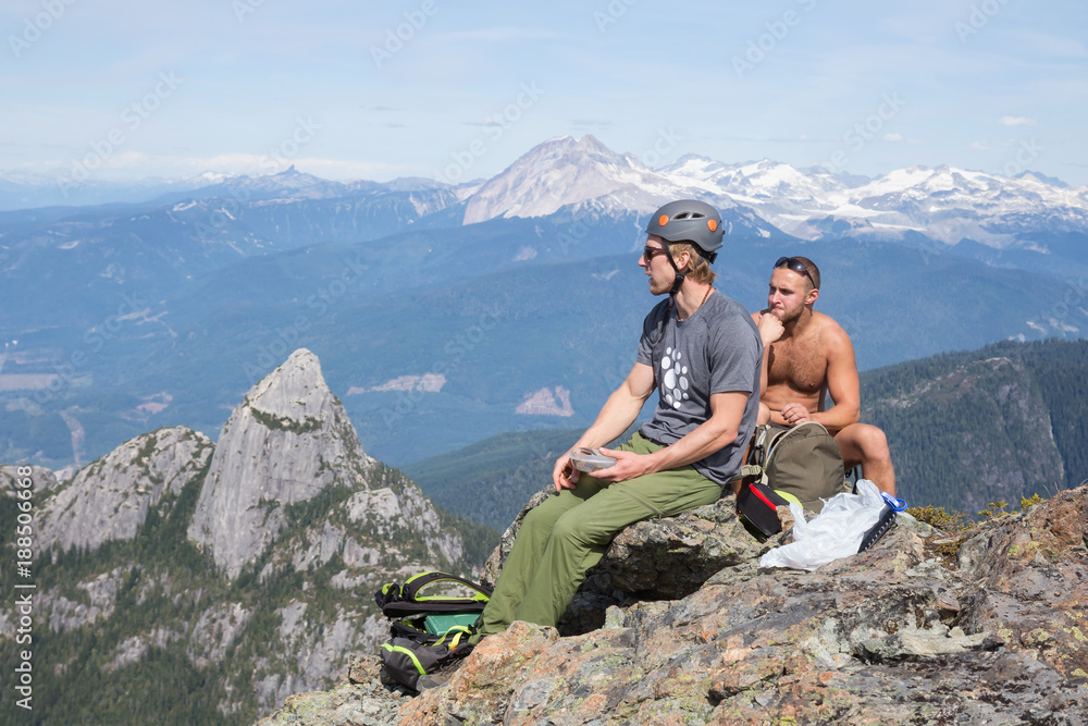 Adventurous people on top of a mountain peak are taking a lunch break.