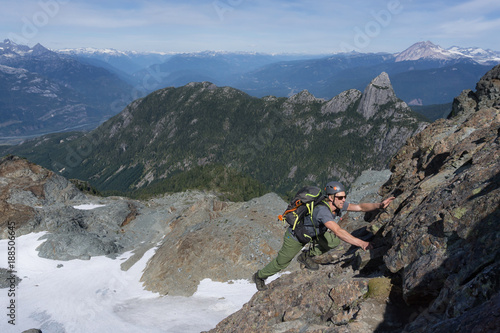 Adventurous man is climbing up the side of a rocky mountain during a sunny summer day. Taken near Squamish, North of Vancouver, British Columbia, Canada.
