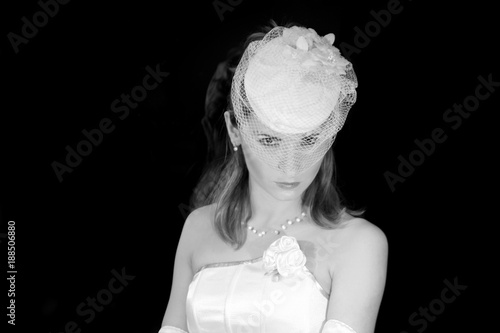 Bride in Wedding Hat Veil, Bridal Fashion Portrait, Beautiful Woman Looking at Camera over Black Background photo