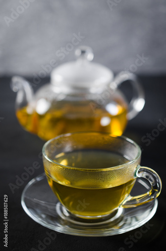 Cup of delicious herbal tea and glass teapot.