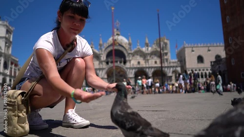 Woman tourist feeding pigeons in the square - St. Marks Square - Venice Italy