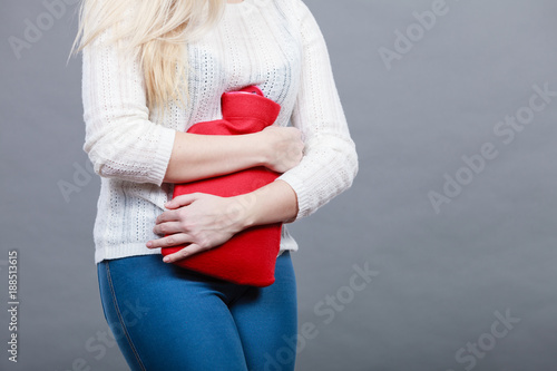 Woman feeling stomach cramps holding hot water bottle