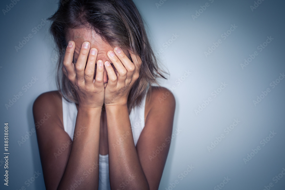 Young woman suffering from a severe depression, anxiety/sudden fear (very harsh lighting is used on this shot to underline/convey the gloomy mood of the scene; color toned image) Young woman suffering from a severe depression, anxiety/sudden fear (very harsh lighting is used on this shot to underline/convey the gloomy mood of the scene; color toned image)