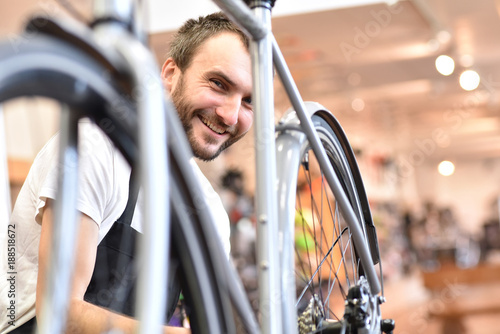 junger sympathischer Fahrradmechaniker repariert Bike im Radladen // young likeable bicycle mechanic repairs bike in a bike shop