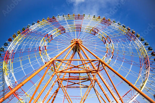 huge modern colorful bright ferris wheel in an amusement park on a blue sky background