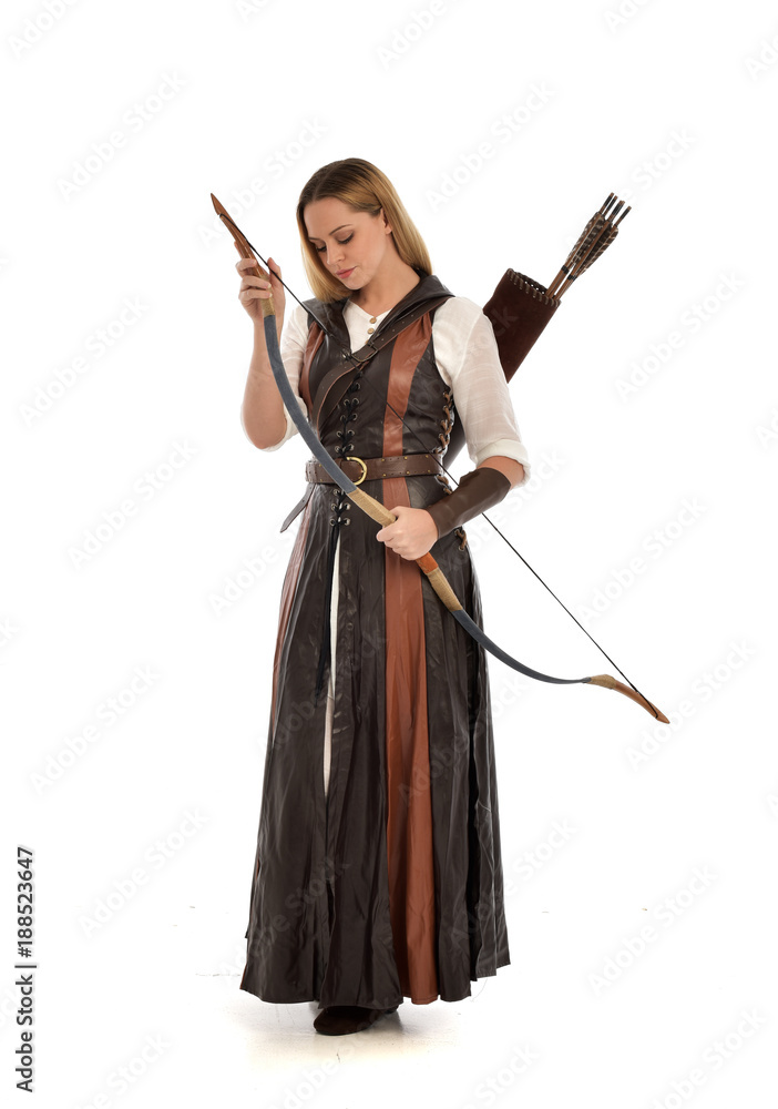 full length portrait of girl wearing brown fantasy costume, holding a bow and arrow. standing pose on white studio background. full length portrait of girl wearing brown fantasy costume, holding a bow and arrow. standing pose on white studio background.