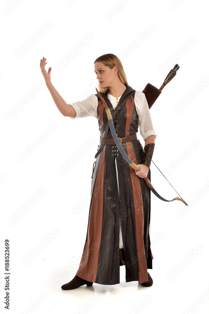 full length portrait of girl wearing brown  fantasy costume, holding a bow and arrow. standing pose on white studio background. 
