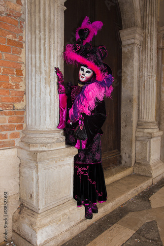 Female Venetian Mask - Cat mask in pink / black elegant costume on St. Mark's Square in Venice with traditional venetian pillar - Venice Carnival