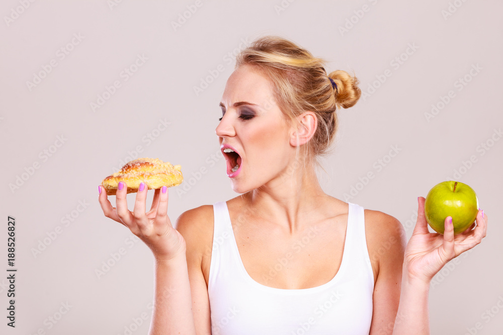 Woman holds cake and fruit in hand choosing Woman holds cake and fruit in hand choosing