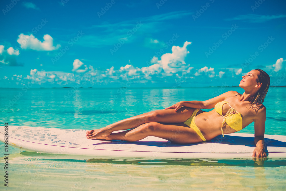 Woman in bikini sunbathing on the beach in Exuma, Bahamas.