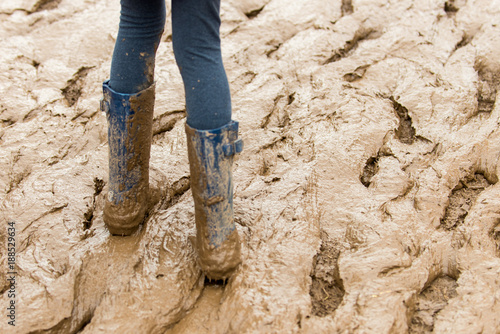 Stockfoto Close up of muddy rubber boots in brown mud | Adobe Stock