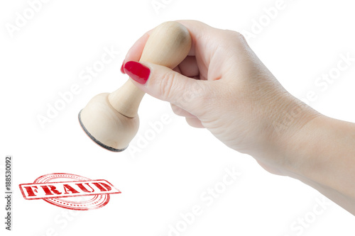 Hand holding a rubber stamp with the word fraud
