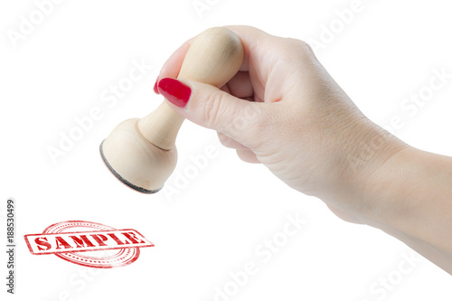 Hand holding a rubber stamp with the word sample
