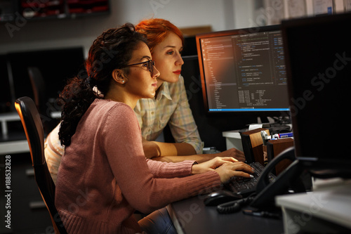 Two female programmers working on new project.They working late at night at the office. photo