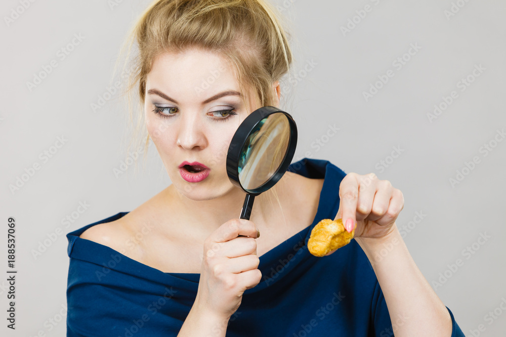 Woman holding magnifying glass investigating bread Woman holding magnifying glass investigating bread