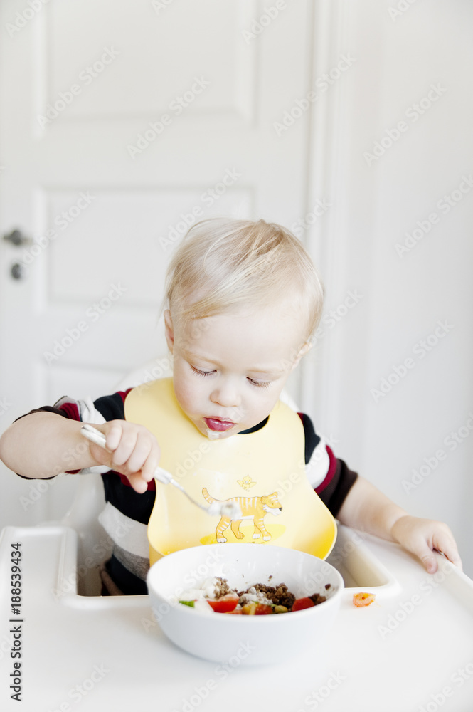 Baby eating breakfast in high chair