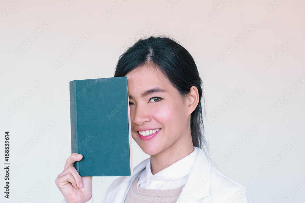 Young Asian businesswoman wearing white suit and holding a book cover her face Young Asian businesswoman wearing white suit and holding a book cover her face