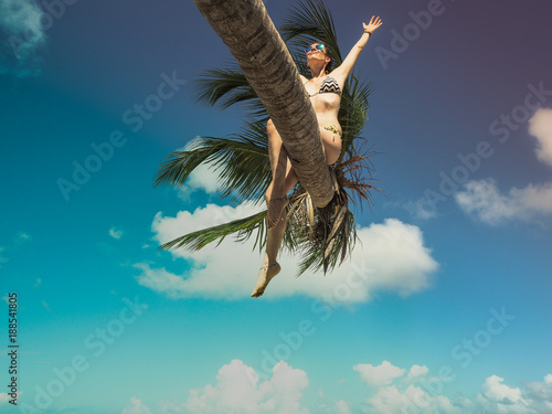 Bikini woman sitting on palm tree at the ocean photo