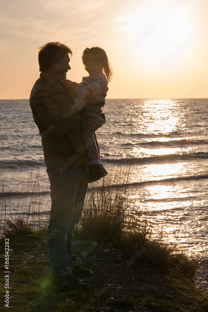 father with a baby girl at sunset by the sea