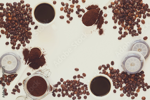 Background with assorted coffee: cups of espresso, coffee beans, powder and capsules on white background. Space for copy. Top view. Flat lay. Toned