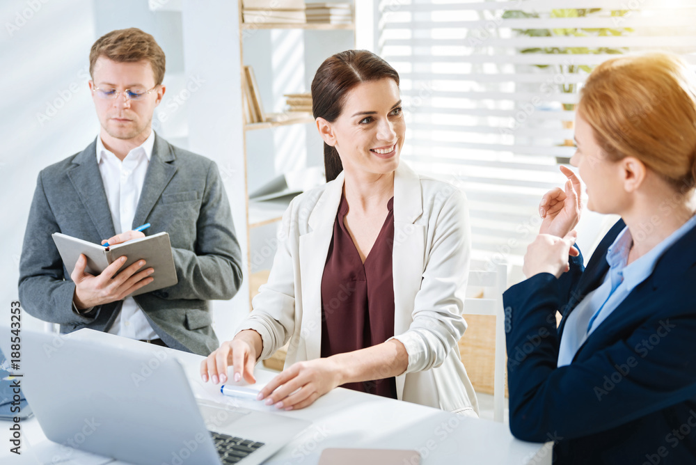 Nice point. Energetic cheerful three colleagues sitting at the table while man writing down and women talking Nice point. Energetic cheerful three colleagues sitting at the table while man writing down and women talking