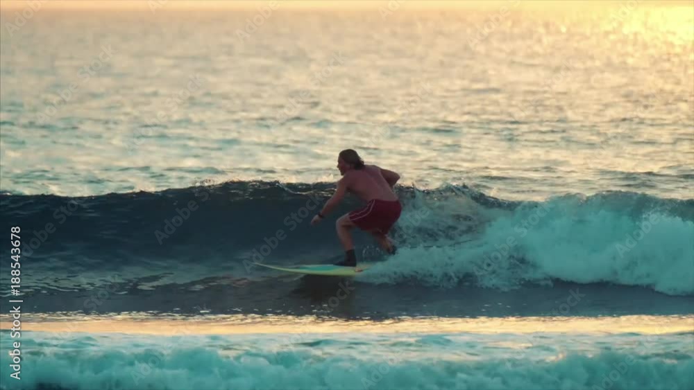 Amateur surfer rides the wave on sunrise surf session Amateur surfer rides the wave on sunrise surf session