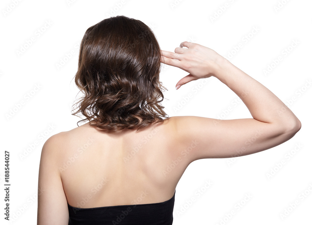 Brunette woman from backside on gray background. Female holding fingers ike a gun at the temple. Brunette woman from backside on gray background. Female holding fingers ike a gun at the temple.