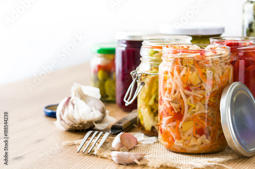 Fotografía Fermented preserved vegetables in jar on wooden table. Copyspace