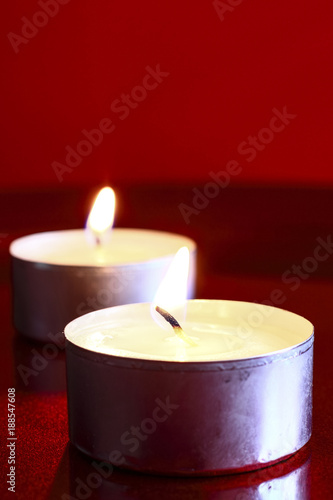 Close up of a burning wax candle against a red background