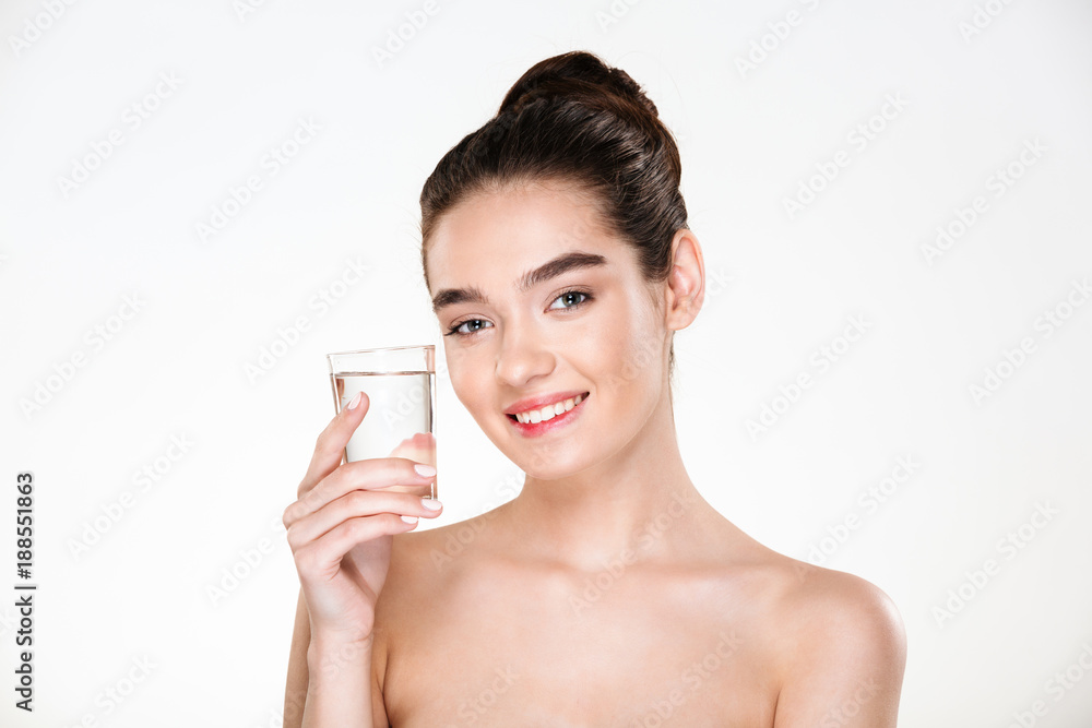 Horizontal picture of happy and healthy woman being half-naked drinking minaral water from transparent glass with smile over white background Horizontal picture of happy and healthy woman being half-naked drinking minaral water from transparent glass with smile over white background