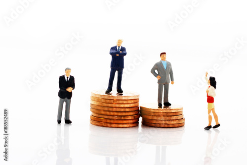 Miniature business people standing on step of coin money. Finance, investment and growth in business concept.