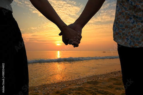 Couple holding hands and beautiful sunset on the beach (Had-Sai-Med-Rak) at Phetchaburi province, Thailand.