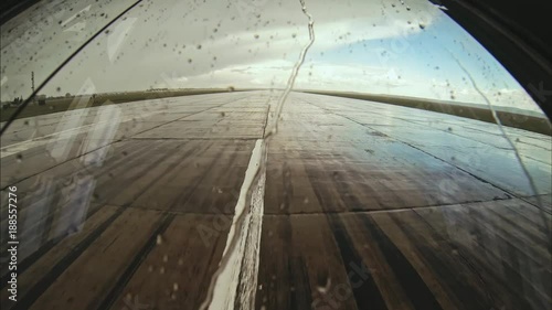 AIRPLANE takes off from a wet runway seen from cockpit. View through the windshield under rainy weather.