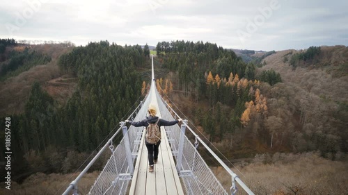 woman walking over hanging rope bridge in germany. wanderlust concept