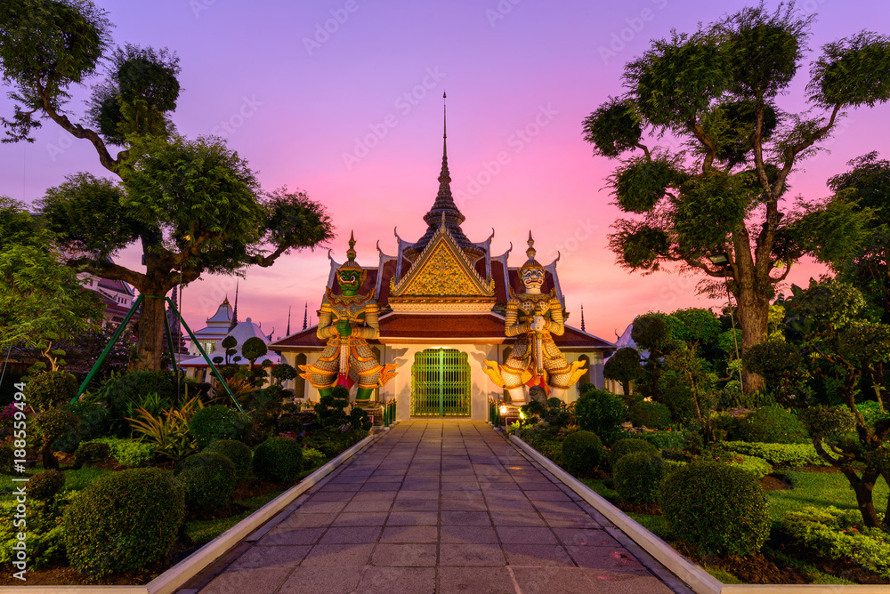 Fototapeta premium Bangkok, Tajlandia - 15 stycznia 2018 r .: gigantyczny posąg przy białej pagodzie w Wat Arun Ratchawararam Ratchawaramahawihan w czasie zachodu słońca
