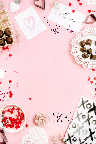 Frame of chocolate candies, heat symbols on pale pink background. Flat lay, top view Valentine's Day or Love concept.